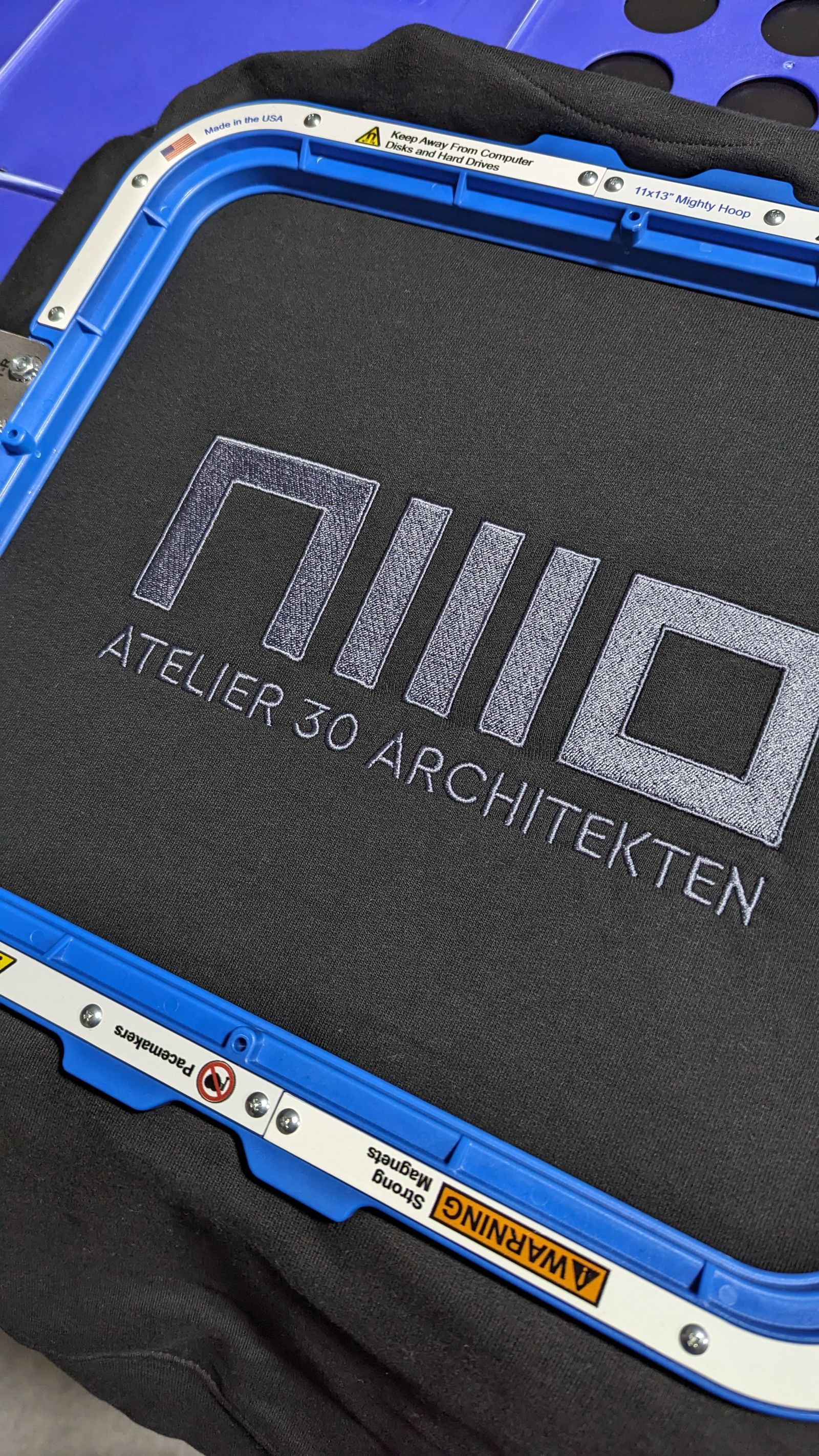 Logo-Stickerei auf schwarzem Textil – Atelier 30 Architekten, Stoff³ Kassel